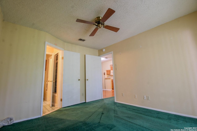 unfurnished bedroom featuring connected bathroom, ceiling fan, light colored carpet, and a textured ceiling