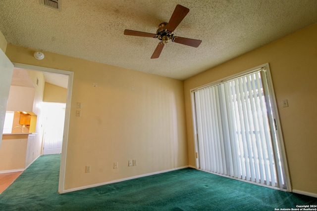 carpeted empty room featuring vaulted ceiling, ceiling fan, and a textured ceiling