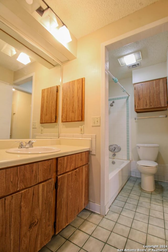 full bathroom featuring vanity, a textured ceiling, tile patterned floors, and tiled shower / bath combo