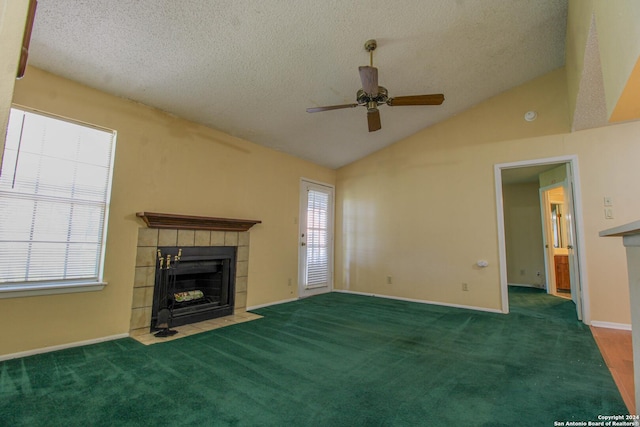 unfurnished living room featuring dark carpet, vaulted ceiling, a tile fireplace, and ceiling fan