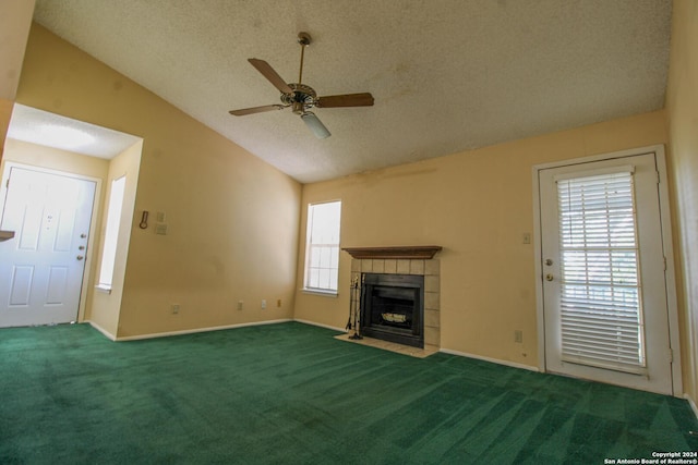 unfurnished living room with vaulted ceiling, carpet flooring, ceiling fan, a fireplace, and a textured ceiling