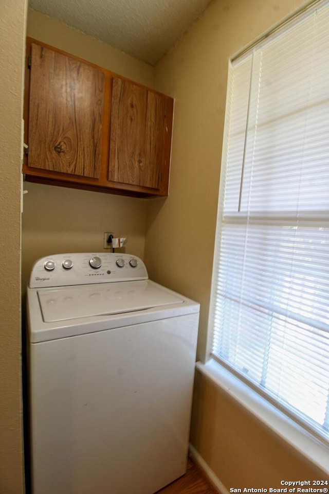 laundry room featuring cabinets, washer / dryer, a textured ceiling, and a wealth of natural light