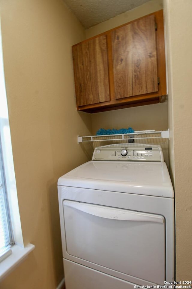 clothes washing area featuring cabinets, washer / dryer, and a textured ceiling