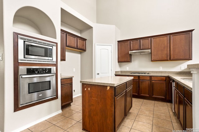 kitchen featuring light stone counters, a center island, light tile patterned floors, and appliances with stainless steel finishes