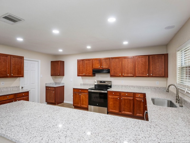 kitchen with light stone countertops, stainless steel electric range oven, and sink