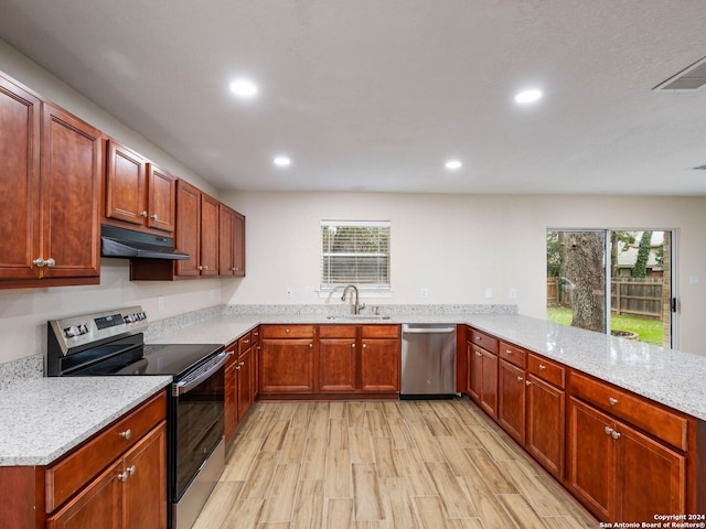 kitchen featuring kitchen peninsula, light stone countertops, stainless steel appliances, sink, and light hardwood / wood-style floors