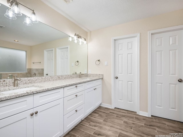 bathroom with hardwood / wood-style flooring, vanity, and a textured ceiling