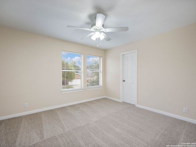 carpeted spare room featuring a textured ceiling and ceiling fan