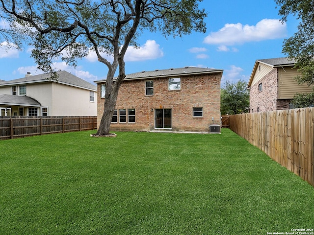 back of property with central air condition unit and a lawn