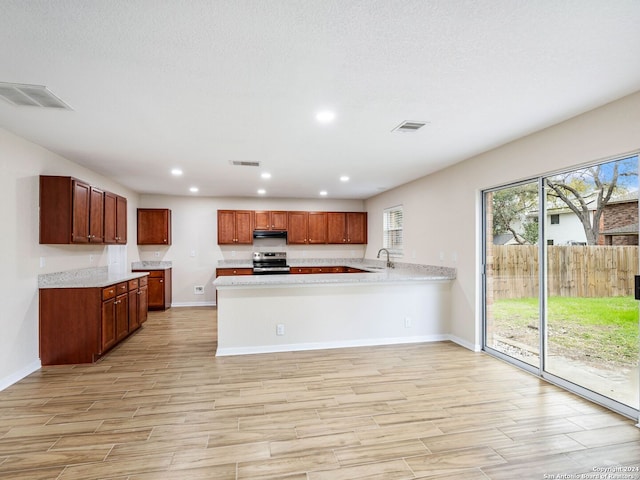 kitchen with electric range, kitchen peninsula, light wood-type flooring, and sink