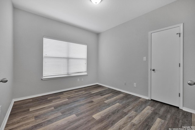 unfurnished room with dark wood-type flooring