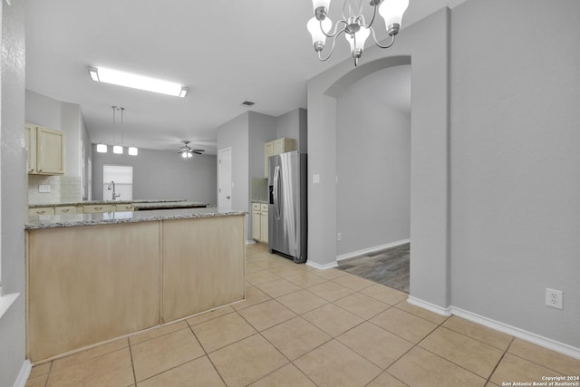 kitchen featuring light stone countertops, kitchen peninsula, ceiling fan with notable chandelier, stainless steel fridge with ice dispenser, and hanging light fixtures