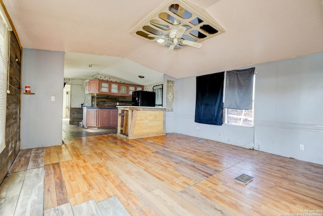 kitchen featuring kitchen peninsula, black fridge, light hardwood / wood-style floors, and lofted ceiling