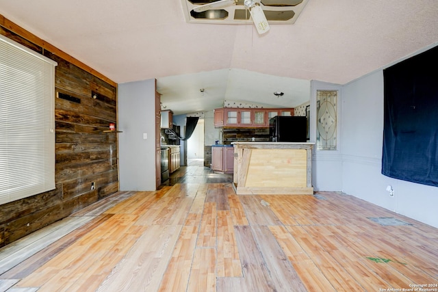 kitchen featuring wood walls, black refrigerator, vaulted ceiling, light hardwood / wood-style flooring, and ceiling fan