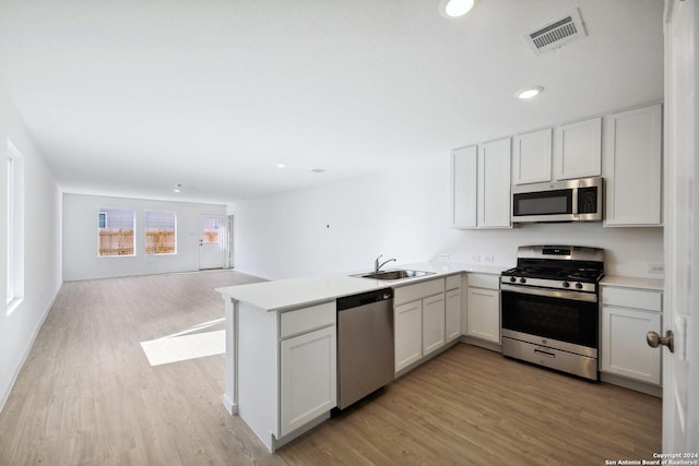 kitchen featuring light hardwood / wood-style floors, sink, kitchen peninsula, and stainless steel appliances