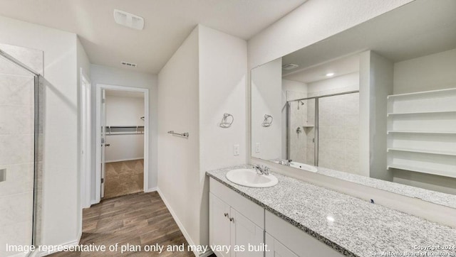 9926 Auger Run, San Antonio, TX 78214 - bathroom featuring a walk in closet, a shower stall, wood finished floors, vanity, and baseboards