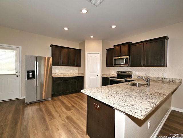 kitchen featuring hardwood / wood-style floors, sink, decorative backsplash, dark brown cabinets, and stainless steel appliances