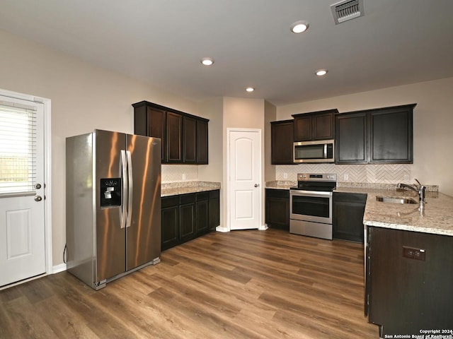 kitchen featuring sink, dark hardwood / wood-style floors, light stone countertops, appliances with stainless steel finishes, and dark brown cabinetry