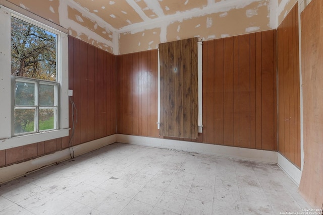 unfurnished room featuring wooden walls and a healthy amount of sunlight