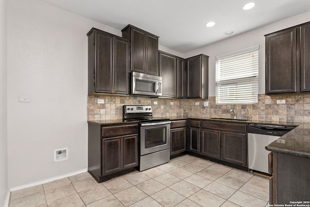 kitchen featuring dark brown cabinetry, sink, decorative backsplash, light tile patterned floors, and appliances with stainless steel finishes