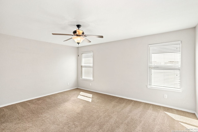 carpeted empty room with a wealth of natural light and ceiling fan