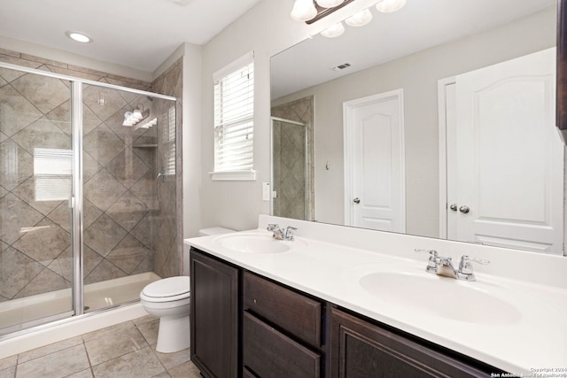 bathroom featuring toilet, vanity, tile patterned floors, and a shower with shower door