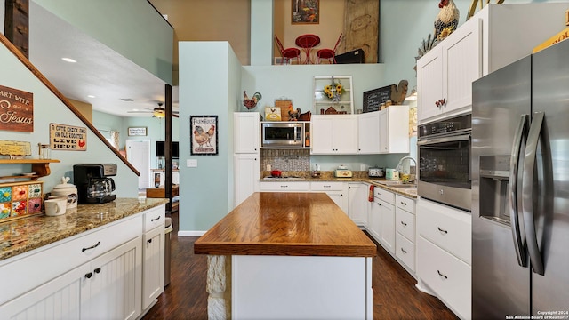 kitchen with dark stone counters, dark wood-type flooring, a kitchen island, and stainless steel appliances