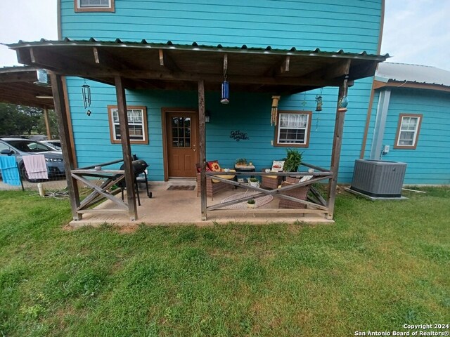 rear view of property featuring a yard, cooling unit, and a patio area