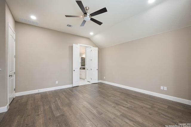 unfurnished bedroom featuring ensuite bath, dark hardwood / wood-style floors, vaulted ceiling, and ceiling fan