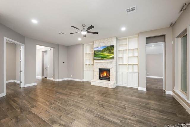 unfurnished living room featuring dark hardwood / wood-style floors, a stone fireplace, and ceiling fan