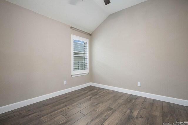 spare room featuring dark hardwood / wood-style floors and lofted ceiling