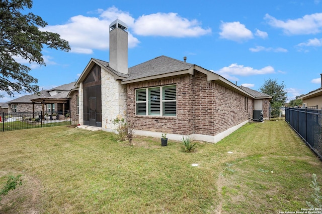 rear view of property featuring central air condition unit and a lawn