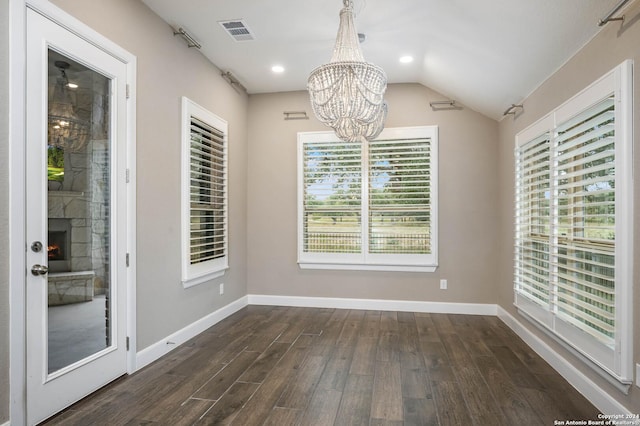 unfurnished dining area featuring vaulted ceiling, dark hardwood / wood-style floors, an inviting chandelier, and a healthy amount of sunlight