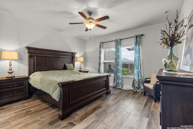 bedroom with ceiling fan, wood-type flooring, and a textured ceiling