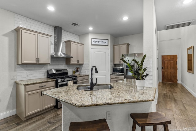 kitchen with sink, wall chimney exhaust hood, dark hardwood / wood-style floors, appliances with stainless steel finishes, and a breakfast bar area