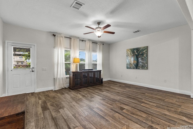 unfurnished living room with a textured ceiling, dark hardwood / wood-style flooring, and ceiling fan