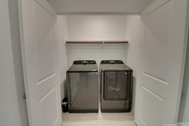 clothes washing area featuring washing machine and dryer and light hardwood / wood-style flooring