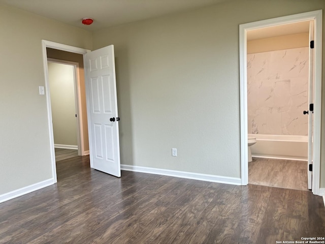 unfurnished bedroom featuring dark hardwood / wood-style flooring and ensuite bath