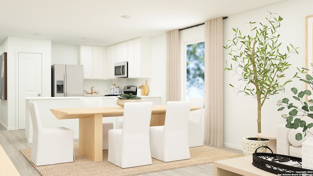 kitchen featuring stainless steel appliances, a kitchen breakfast bar, white cabinets, light hardwood / wood-style floors, and a kitchen island