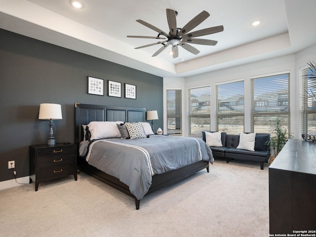 bedroom with a tray ceiling, ceiling fan, and light carpet