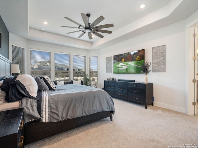 carpeted bedroom featuring a tray ceiling and ceiling fan