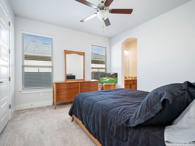 bedroom with ensuite bathroom, ceiling fan, and light colored carpet