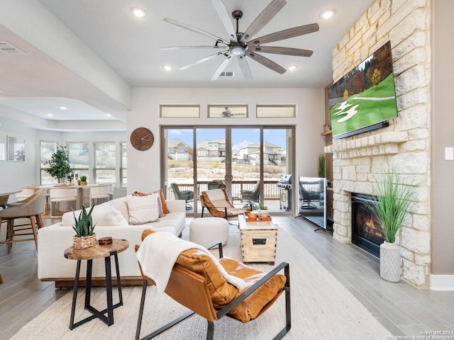 living room with a fireplace, light hardwood / wood-style floors, and ceiling fan