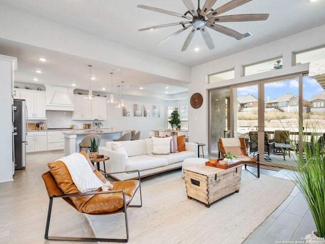 living room featuring ceiling fan, light wood-type flooring, and sink