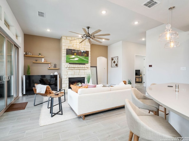 living room featuring ceiling fan, light hardwood / wood-style floors, and a fireplace