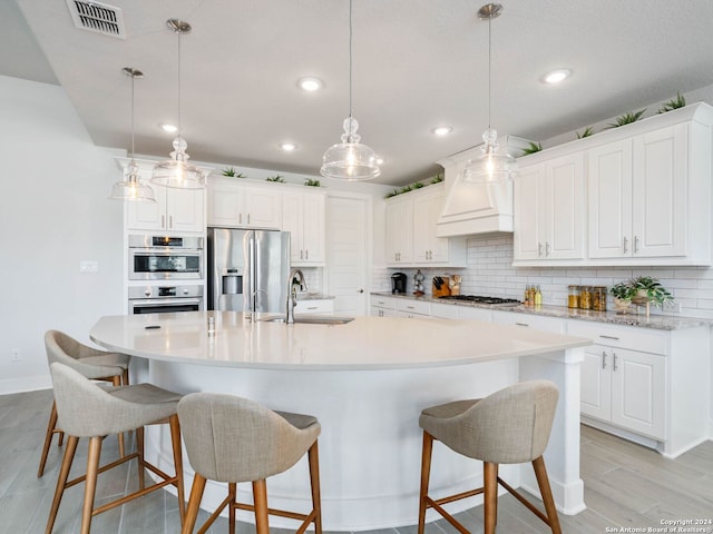 kitchen featuring appliances with stainless steel finishes, hanging light fixtures, a spacious island, and sink