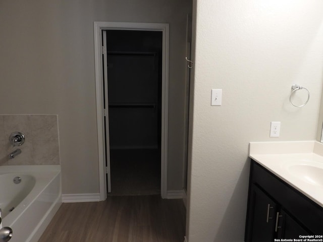 bathroom with hardwood / wood-style floors, vanity, and a washtub