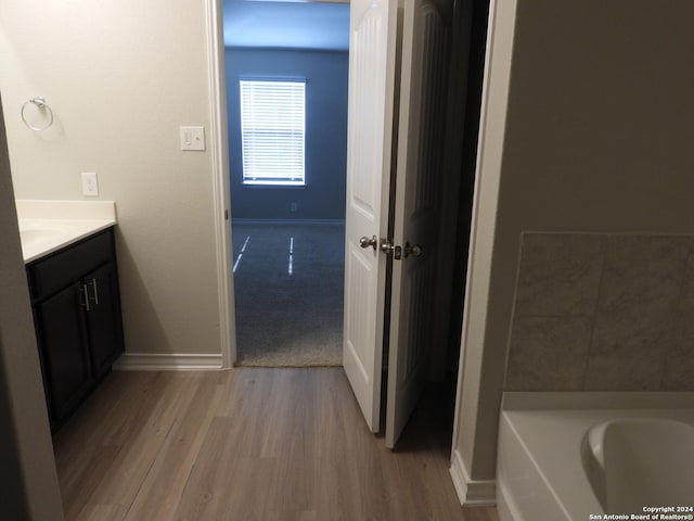 bathroom with hardwood / wood-style floors, vanity, and a tub