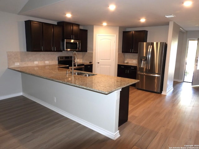 kitchen featuring light hardwood / wood-style floors, sink, kitchen peninsula, and stainless steel appliances