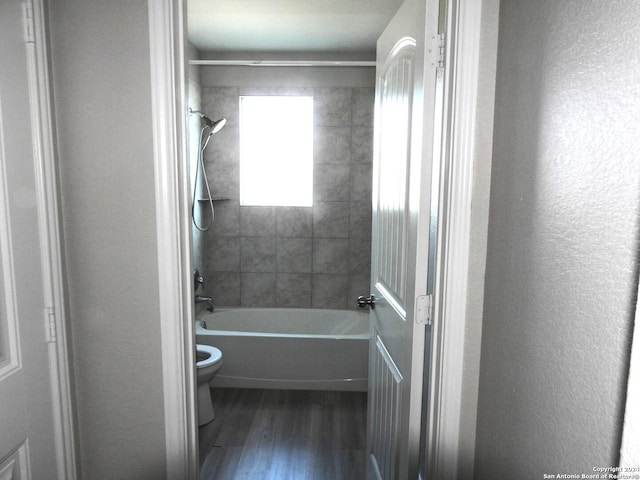 bathroom with tiled shower / bath, wood-type flooring, and toilet